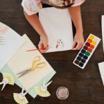 Person dessinant des lapins avec des crayons et des aquarelles sur une table en bois