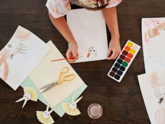 Person dessinant des lapins avec des crayons et des aquarelles sur une table en bois