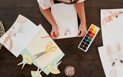 Person dessinant des lapins avec des crayons et des aquarelles sur une table en bois