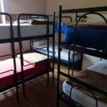 Chambre avec plusieurs lits superposés à cadre métallique, matelas blancs et rouges visibles