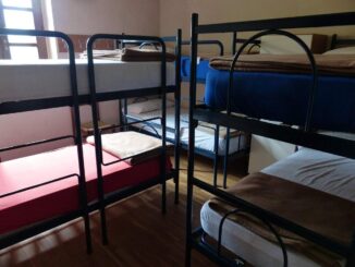 Chambre avec plusieurs lits superposés à cadre métallique, matelas blancs et rouges visibles