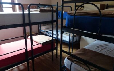 Chambre avec plusieurs lits superposés à cadre métallique, matelas blancs et rouges visibles