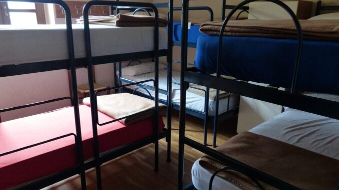 Chambre avec plusieurs lits superposés à cadre métallique, matelas blancs et rouges visibles