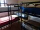 Chambre avec plusieurs lits superposés à cadre métallique, matelas blancs et rouges visibles