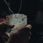 Une personne tient plusieurs cartes de jeu dans une voiture sombre