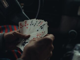 Une personne tient plusieurs cartes de jeu dans une voiture sombre