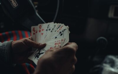 Une personne tient plusieurs cartes de jeu dans une voiture sombre