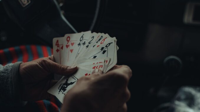 Une personne tient plusieurs cartes de jeu dans une voiture sombre