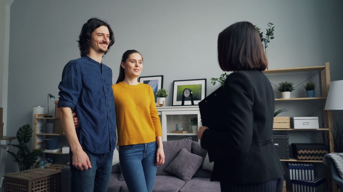 Trois individus en conversation dans un salon décoré de meubles et d'objets personnels