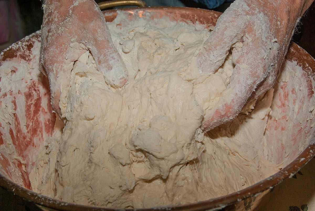 Mains farineuses modelant pâte dans bol en cuivre Mains farineuses modelant pâte dans bol en cuivre