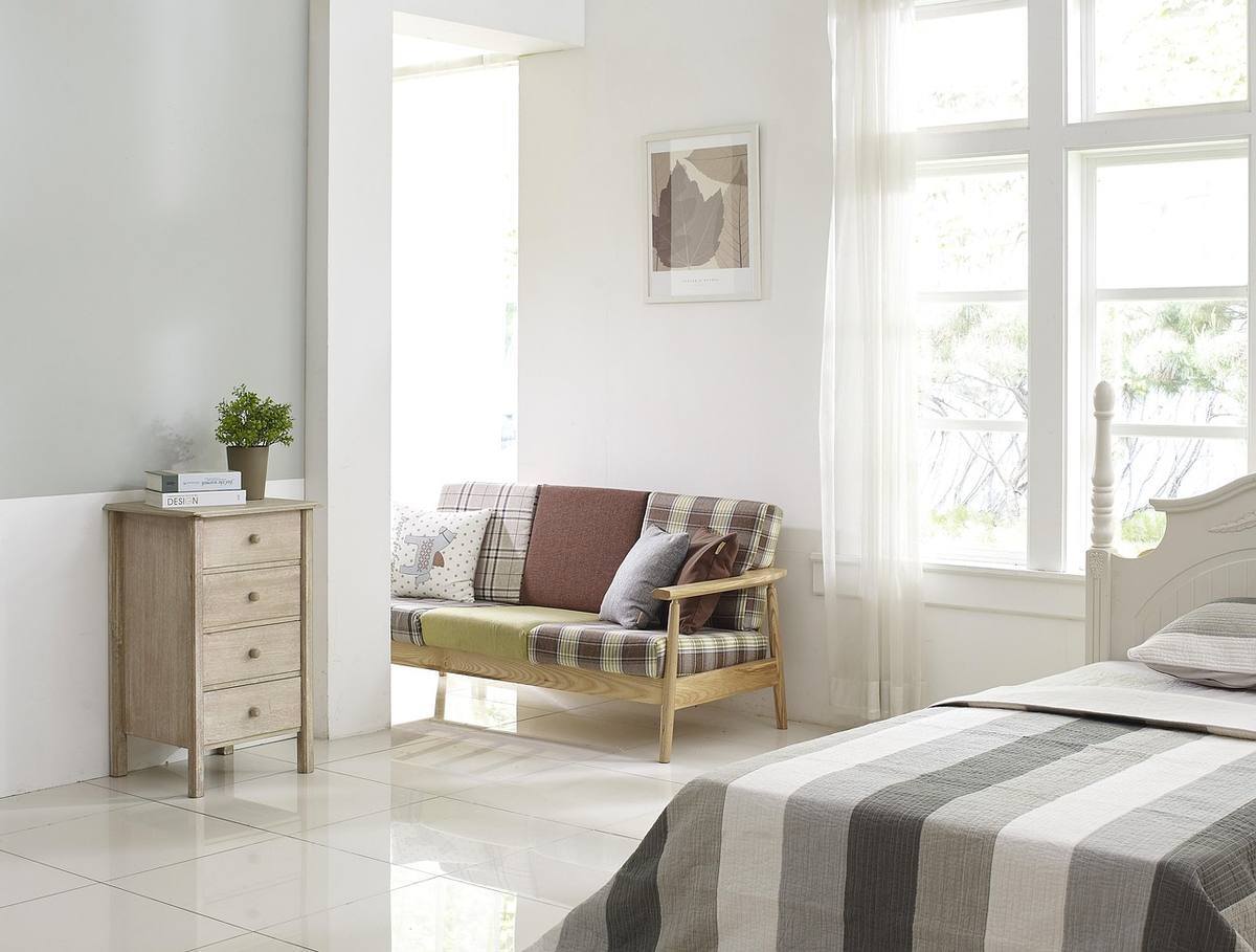 Chambre spacieuse avec canapé en bois, lit rayé et grandes fenêtres claires Chambre spacieuse avec canapé en bois, lit rayé et grandes fenêtres claires