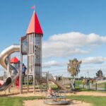Enfants jouant sur une structure de jeu avec un toboggan et un château dans un parc
