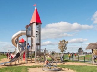 Enfants jouant sur une structure de jeu avec un toboggan et un château dans un parc