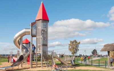 Enfants jouant sur une structure de jeu avec un toboggan et un château dans un parc