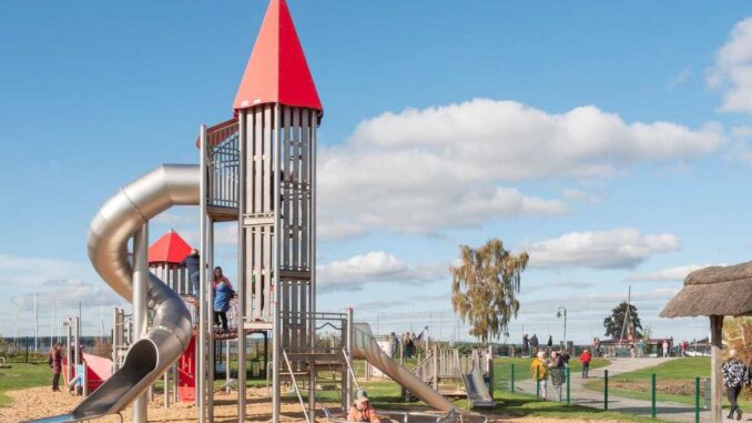 Enfants jouant sur une structure de jeu avec un toboggan et un château dans un parc