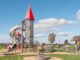 Enfants jouant sur une structure de jeu avec un toboggan et un château dans un parc