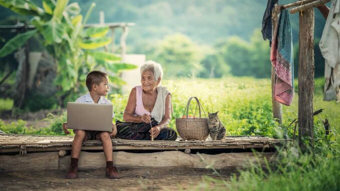 Un jeune garçon utilise un ordinateur portable à côté d'une grand-mère