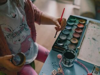 Enfant avec pinceau, peintures, et objets sur une table