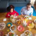 Famille partageant un repas de pâques avec divers plats sur une table en bois dans un salon