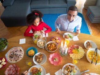 Famille partageant un repas de pâques avec divers plats sur une table en bois dans un salon