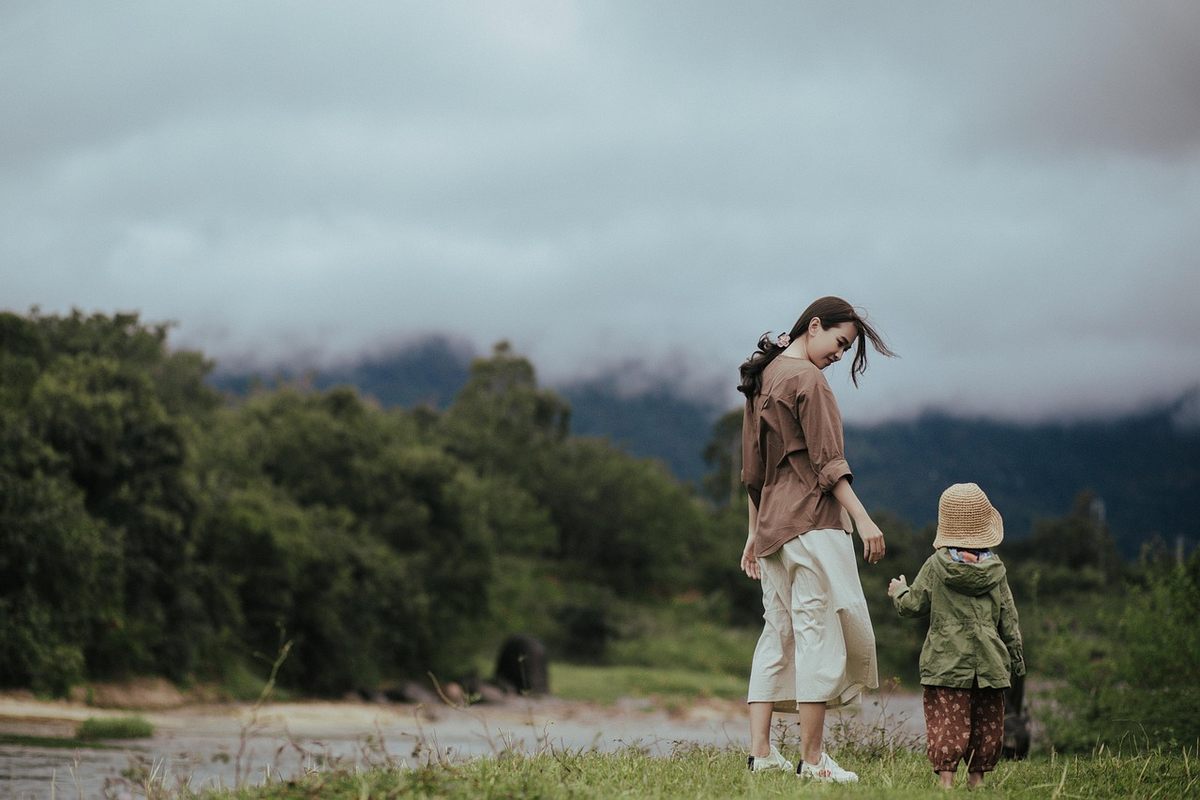 Femme et enfant marchant près d'un lac sous un ciel nuageux Femme et enfant marchant près d'un lac sous un ciel nuageux