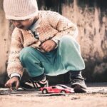 Un enfant joue avec une petite voiture rouge sur le sol