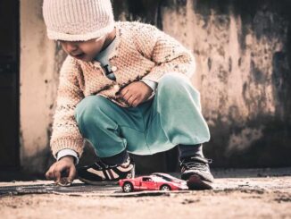 Un enfant joue avec une petite voiture rouge sur le sol