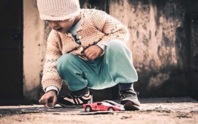 Un enfant joue avec une petite voiture rouge sur le sol