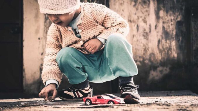 Un enfant joue avec une petite voiture rouge sur le sol