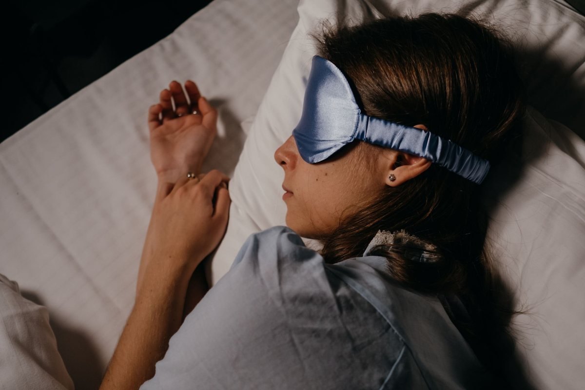 Femme endormie sous couette avec masque pour les yeux et oreillettes Femme endormie sous couette avec masque pour les yeux et oreillettes