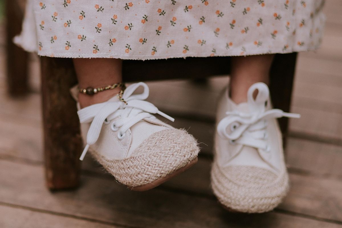 Enfant assis sur banc, chaussures tressées, plancher en bois Enfant assis sur banc, chaussures tressées, plancher en bois