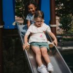Enfants sur une glissière dans un parc, structures bleues et végétation environnante