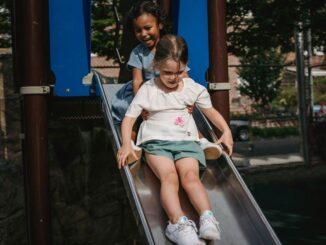 Enfants sur une glissière dans un parc, structures bleues et végétation environnante