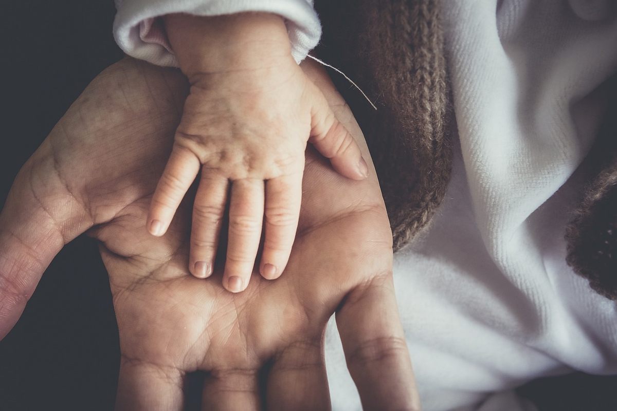 Une main d'adulte accueille doucement la petite main d'un enfant