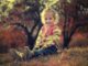 Une petite fille assise sur l'herbe, souriante, en pull rayé, avec des arbres automnaux
