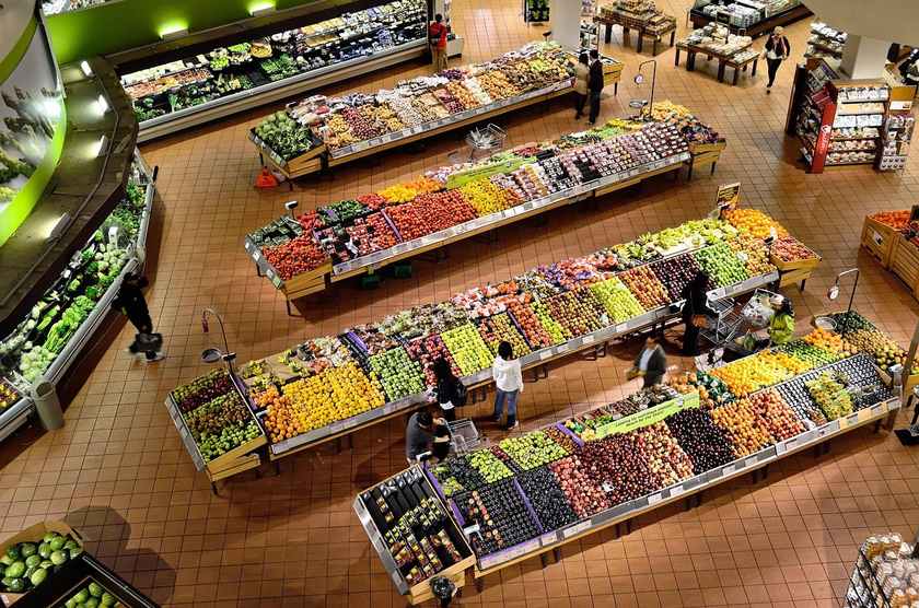 Aile de fruits et légumes dans un supermarché, clients observant les produits Aile de fruits et légumes dans un supermarché, clients observant les produits