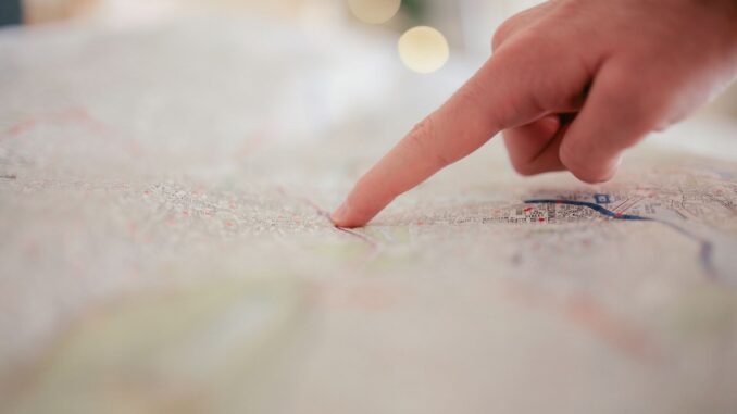 Une main indique un point précis sur une carte détaillée