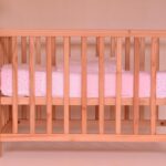Un berceau en bois avec un matelas blanc et rose