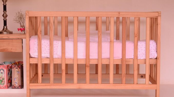Un berceau en bois avec un matelas blanc et rose