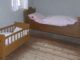 Chambre aménagée avec un lit adulte et un petit berceau en bois clair pour enfant