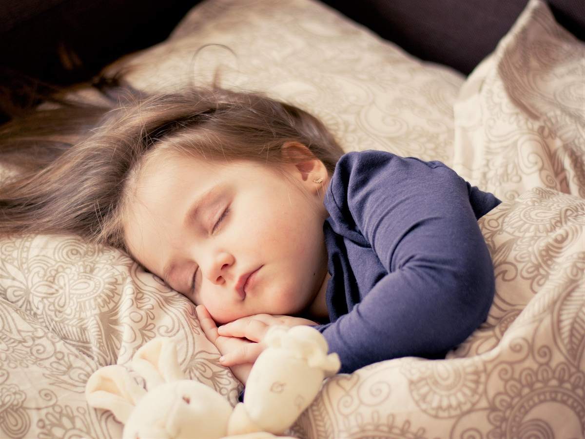 Une petite fille dort paisiblement serrant une peluche Une petite fille dort paisiblement serrant une peluche