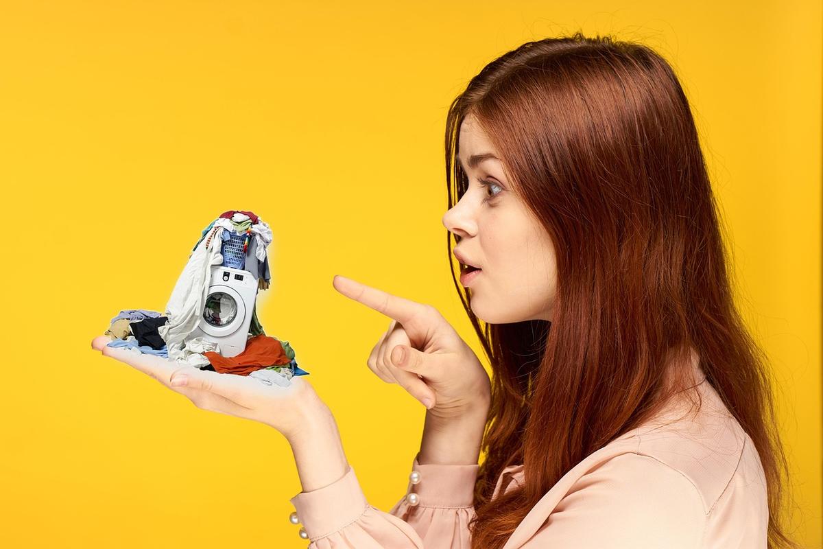 Une femme montre un petit appareil lavage avec linge pointant du doigt Une femme montre un petit appareil lavage avec linge pointant du doigt