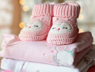 Chaussons tricotés roses et bodies pastel empilés, décor lumineux