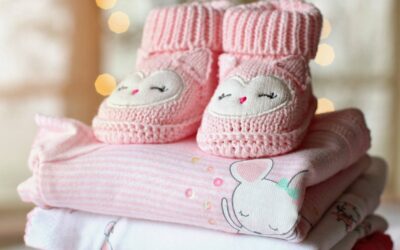 Chaussons tricotés roses et bodies pastel empilés, décor lumineux